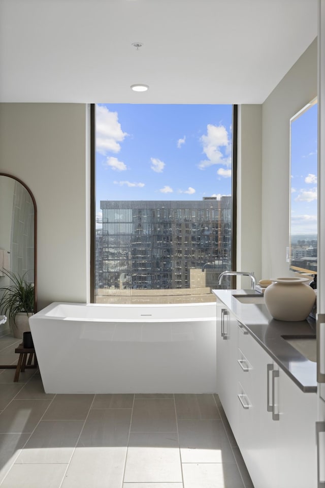 bathroom featuring a wealth of natural light, a view of city, a soaking tub, and tile patterned floors