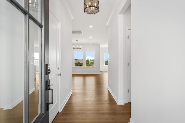 hall with baseboards, dark wood-type flooring, crown molding, a chandelier, and recessed lighting