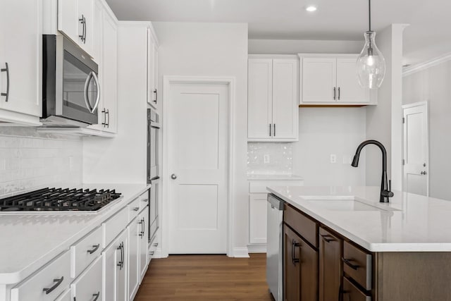 kitchen with hanging light fixtures, appliances with stainless steel finishes, a sink, and white cabinets