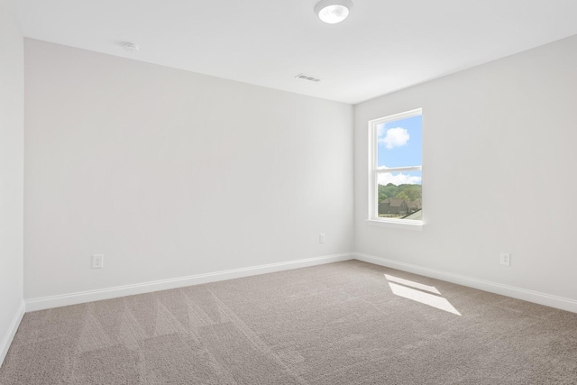 carpeted spare room with visible vents and baseboards