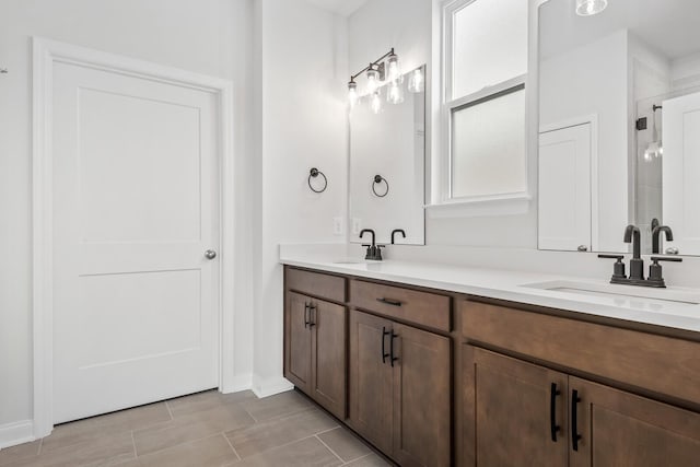 bathroom with a sink, a shower stall, and double vanity