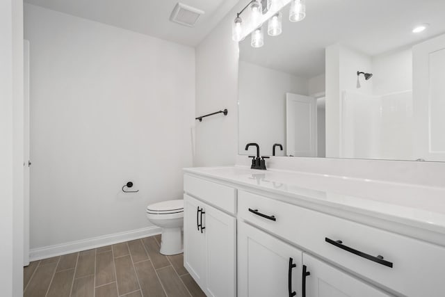 full bath featuring baseboards, visible vents, toilet, vanity, and wood finish floors