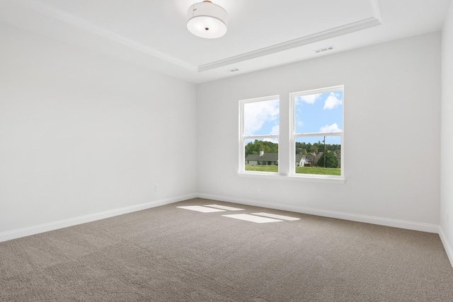 carpeted spare room featuring a tray ceiling, visible vents, and baseboards