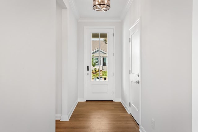 doorway featuring baseboards, an inviting chandelier, wood finished floors, and crown molding