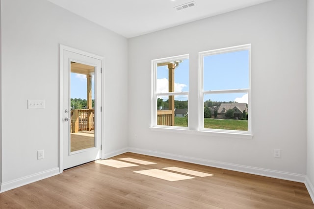 spare room with light wood-style flooring, visible vents, and baseboards