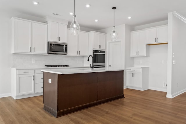 kitchen featuring visible vents, white cabinets, light countertops, hanging light fixtures, and stainless steel microwave