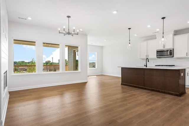 kitchen featuring light countertops, stainless steel microwave, hanging light fixtures, visible vents, and white cabinets