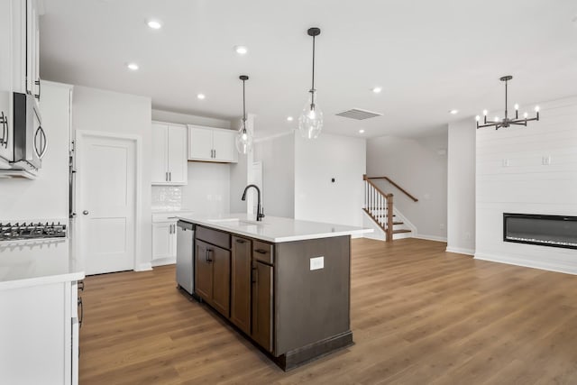 kitchen with white cabinets, a kitchen island with sink, stainless steel appliances, light countertops, and a sink