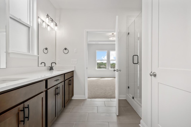 bathroom with double vanity, a stall shower, tile patterned flooring, and a sink