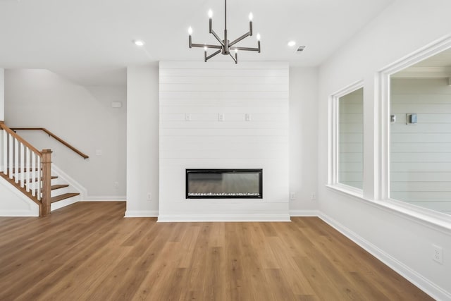 unfurnished living room featuring visible vents, stairway, a large fireplace, wood finished floors, and baseboards