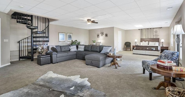 living room with stairs, baseboards, a drop ceiling, and carpet flooring