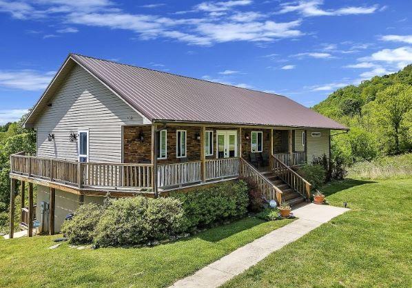 ranch-style house with metal roof, a porch, and a front lawn