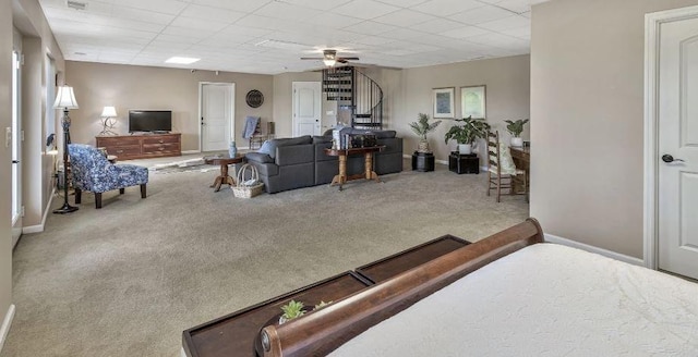 carpeted living area with a ceiling fan, a paneled ceiling, stairway, and baseboards