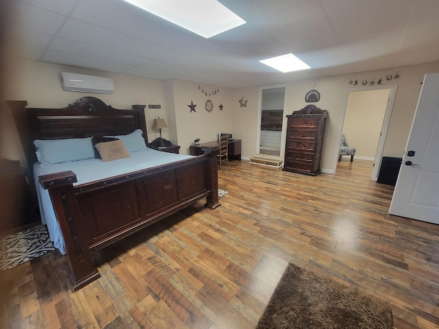 bedroom with baseboards, an AC wall unit, and wood finished floors