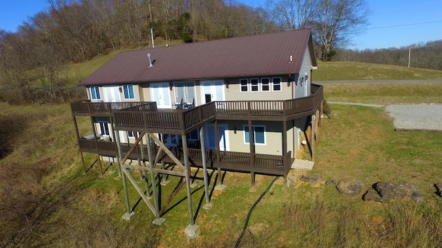 rear view of property featuring a yard, metal roof, and a wooden deck