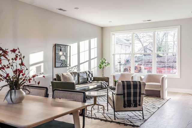 living area featuring light wood finished floors, visible vents, and baseboards