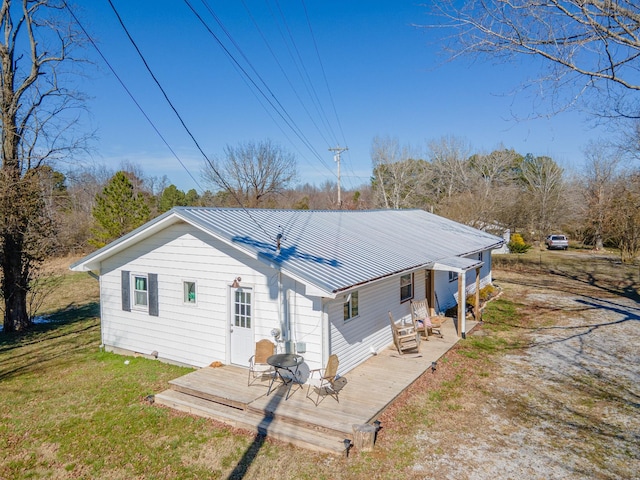 back of house with metal roof, a deck, and a lawn