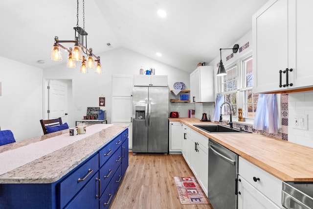 kitchen with appliances with stainless steel finishes, a sink, white cabinetry, and blue cabinets