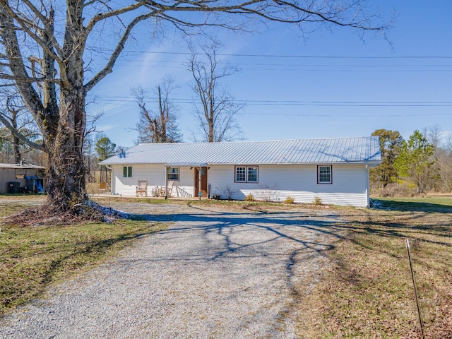 view of front facade featuring metal roof, driveway, and a front lawn