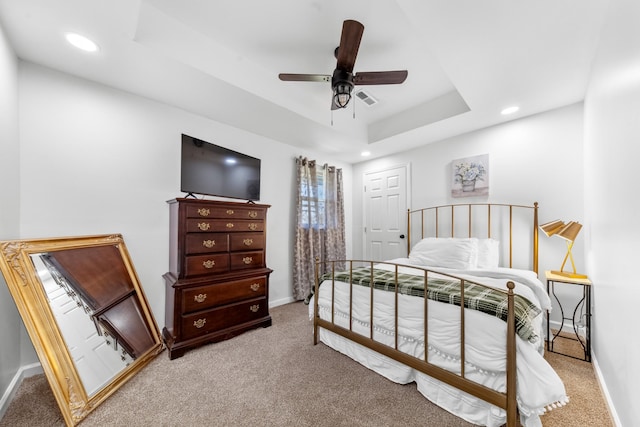 carpeted bedroom featuring a tray ceiling, recessed lighting, visible vents, ceiling fan, and baseboards