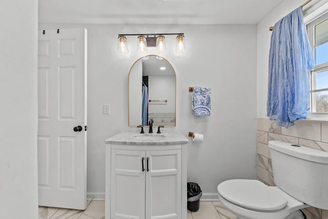 bathroom with marble finish floor, vanity, toilet, and baseboards