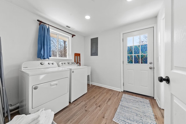 washroom featuring washing machine and dryer, laundry area, visible vents, light wood-type flooring, and electric panel