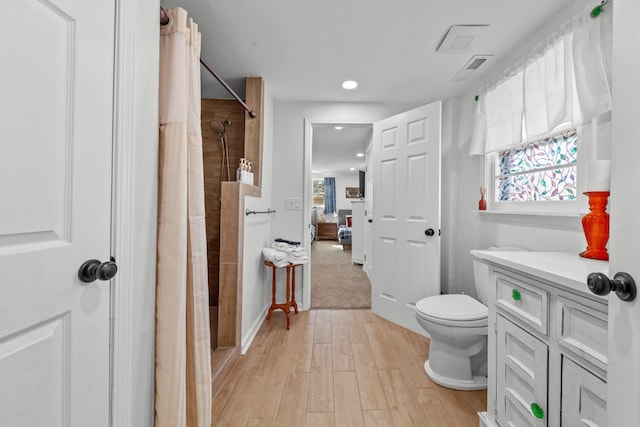 ensuite bathroom featuring toilet, connected bathroom, a tile shower, and wood finished floors