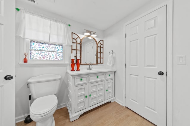 bathroom featuring toilet, baseboards, wood finished floors, and vanity