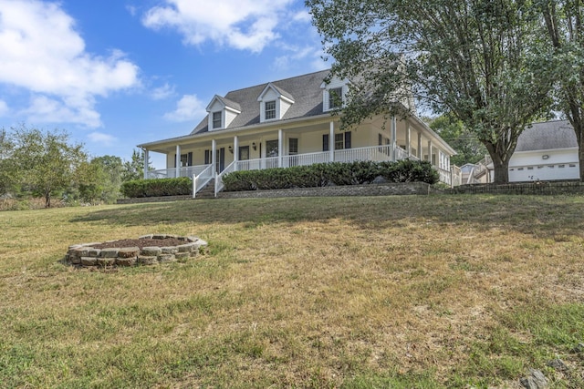 farmhouse inspired home featuring a porch, a front yard, and a fire pit