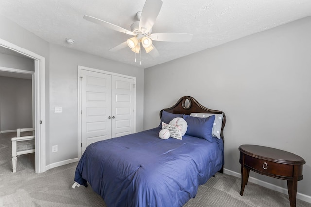 carpeted bedroom with a textured ceiling, a closet, a ceiling fan, and baseboards