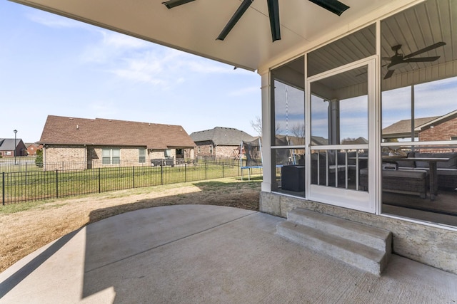 view of patio / terrace with a trampoline, a sunroom, ceiling fan, fence, and a residential view