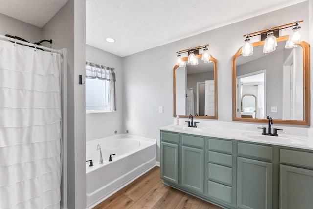 bathroom featuring double vanity, a sink, a bath, and wood finished floors