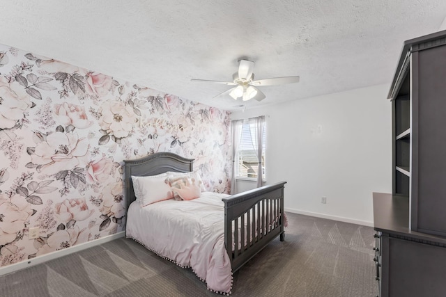 bedroom with dark colored carpet, a ceiling fan, a textured ceiling, baseboards, and wallpapered walls