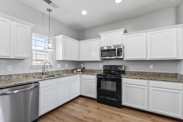 kitchen with appliances with stainless steel finishes, white cabinets, visible vents, and a sink