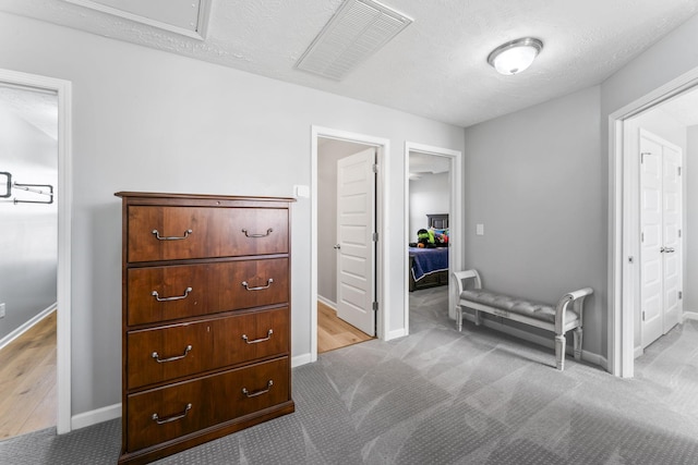 carpeted bedroom featuring visible vents, a textured ceiling, and baseboards