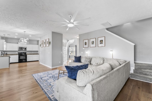 living area with light wood-style floors, visible vents, arched walkways, and a textured ceiling