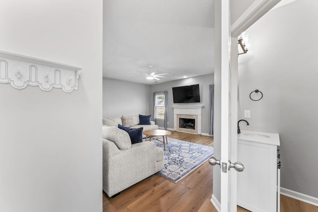 living area with ceiling fan, baseboards, wood finished floors, and a high end fireplace