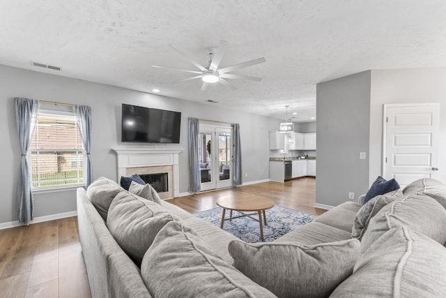 living room featuring light wood-style floors, baseboards, visible vents, and a high end fireplace