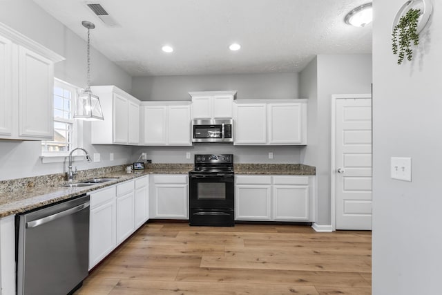 kitchen featuring stainless steel appliances, visible vents, light wood-style floors, white cabinetry, and a sink