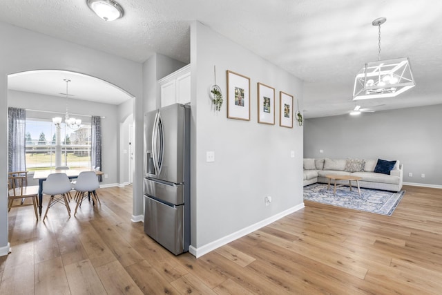 kitchen with white cabinets, light wood-style flooring, arched walkways, and stainless steel refrigerator with ice dispenser