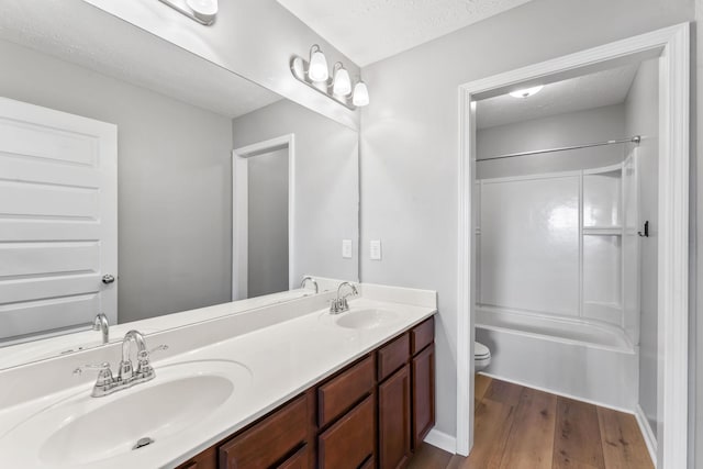 bathroom featuring double vanity, a sink, a textured ceiling, and wood finished floors