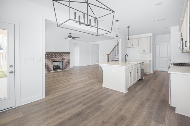 kitchen with a kitchen island with sink, white cabinets, light countertops, and open floor plan