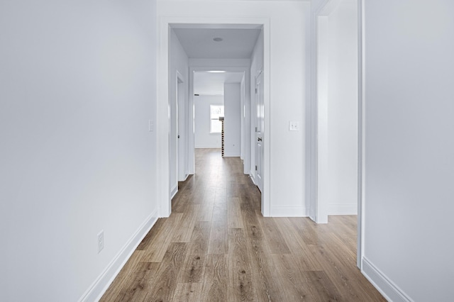 hall with baseboards and light wood-style floors