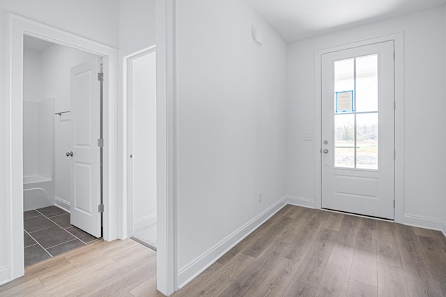 doorway featuring light wood-style flooring and baseboards