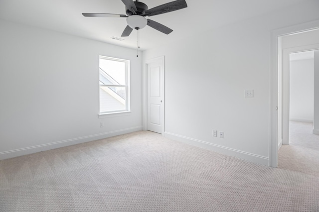 spare room with a ceiling fan, light colored carpet, and baseboards