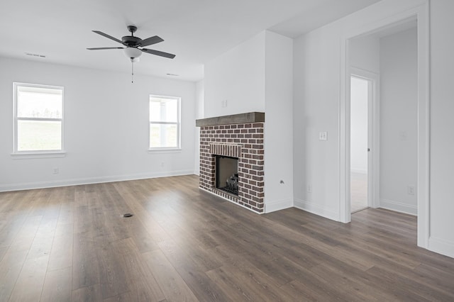 unfurnished living room featuring dark wood-type flooring, a fireplace, baseboards, and a ceiling fan