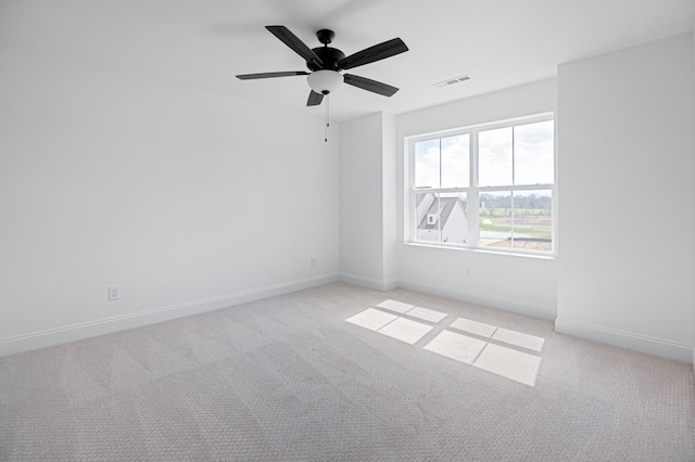 empty room with light colored carpet, visible vents, ceiling fan, and baseboards