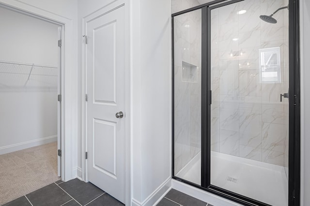 full bath featuring a stall shower, tile patterned flooring, a spacious closet, and baseboards