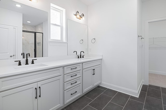 bathroom with a shower stall, a spacious closet, a sink, and tile patterned floors