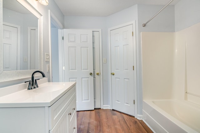 full bath with washtub / shower combination, vanity, and wood finished floors